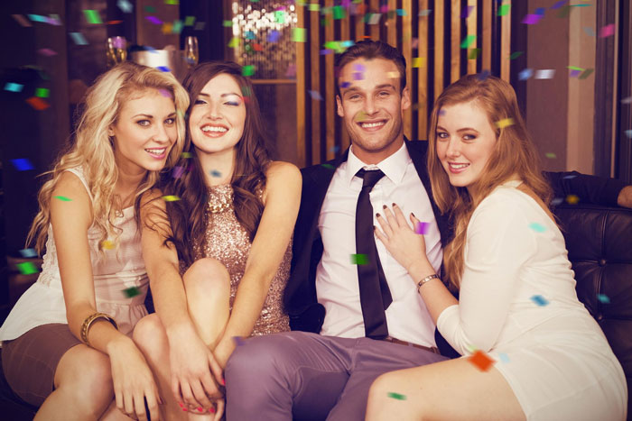 Group of young adults celebrating indoors with confetti, capturing a moment related to wife surprise visitor and pregnancy claim.